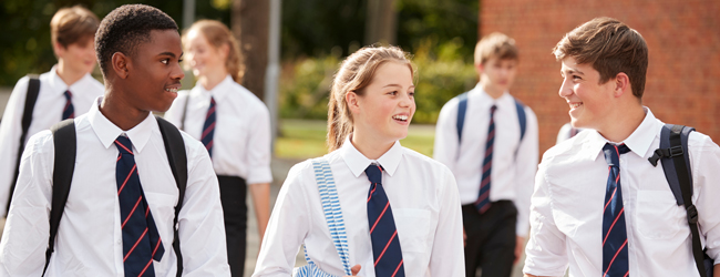Preparing for a univerity studium at an Oxford Summer School Three young students walking and talking together wearing a student uniform